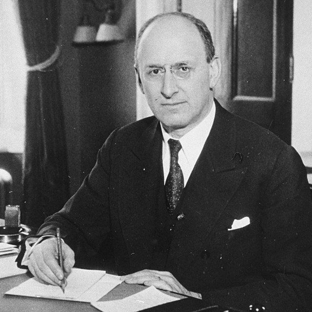 A man seated at a desk with papers.