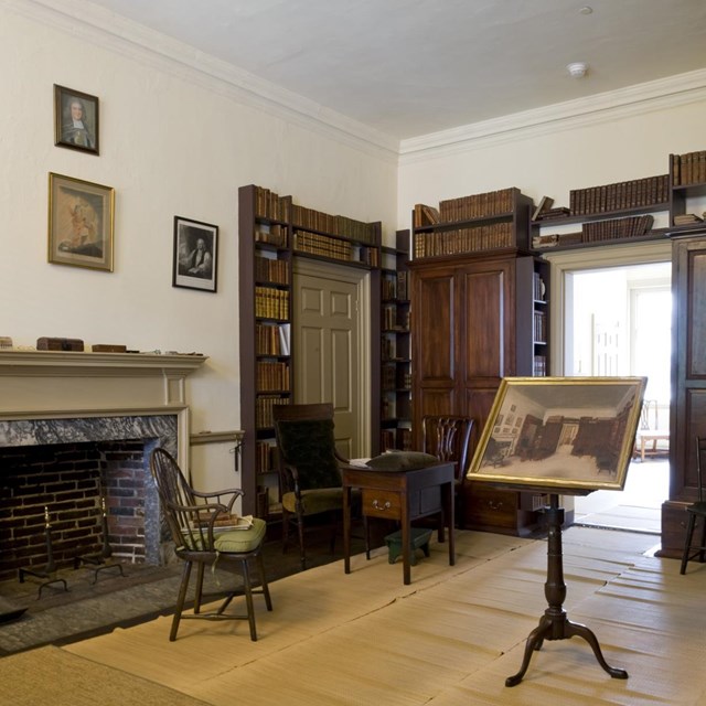 Color photo of study restored to 19th century appearance, with bookcases and Windsor chair.