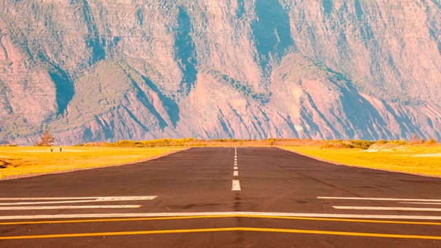 A runway stretches towards large cliffs