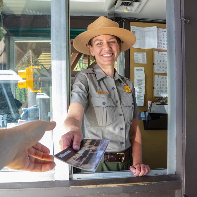 Ranger handing a park brochure out a booth window