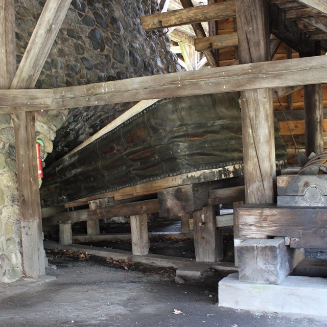 Stone wall with large air bellows and wooden wheel.