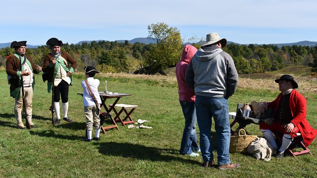 Group of 18th century soldiers talking with visitors