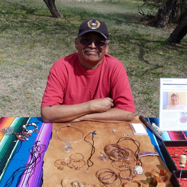 man in front of table with bracelets and jewelry