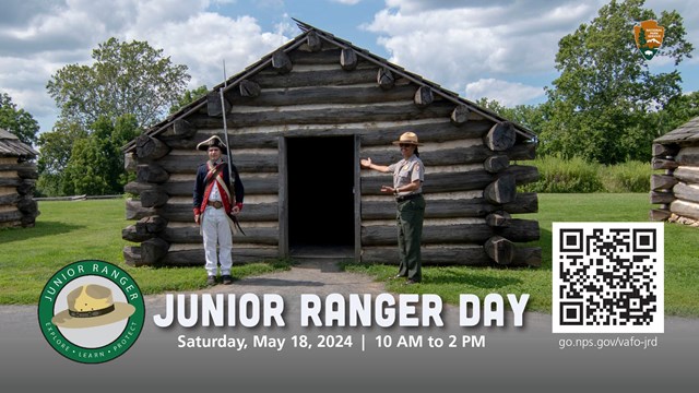 Ranger wearing a soldier uniform and a ranger wearing a park ranger uniform stand outside a log hut