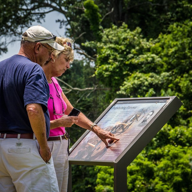 Two visitors read an informational wayside sign