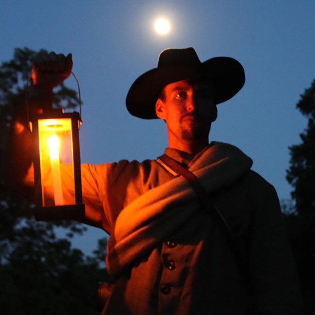 A soldier hold a lantern at night.