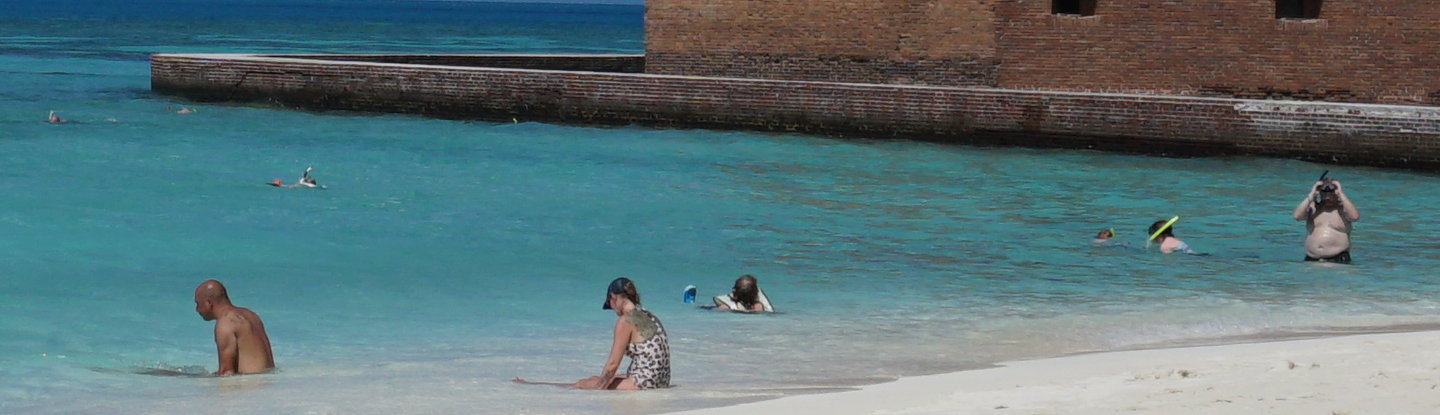 People on a beach in front of a brick structure