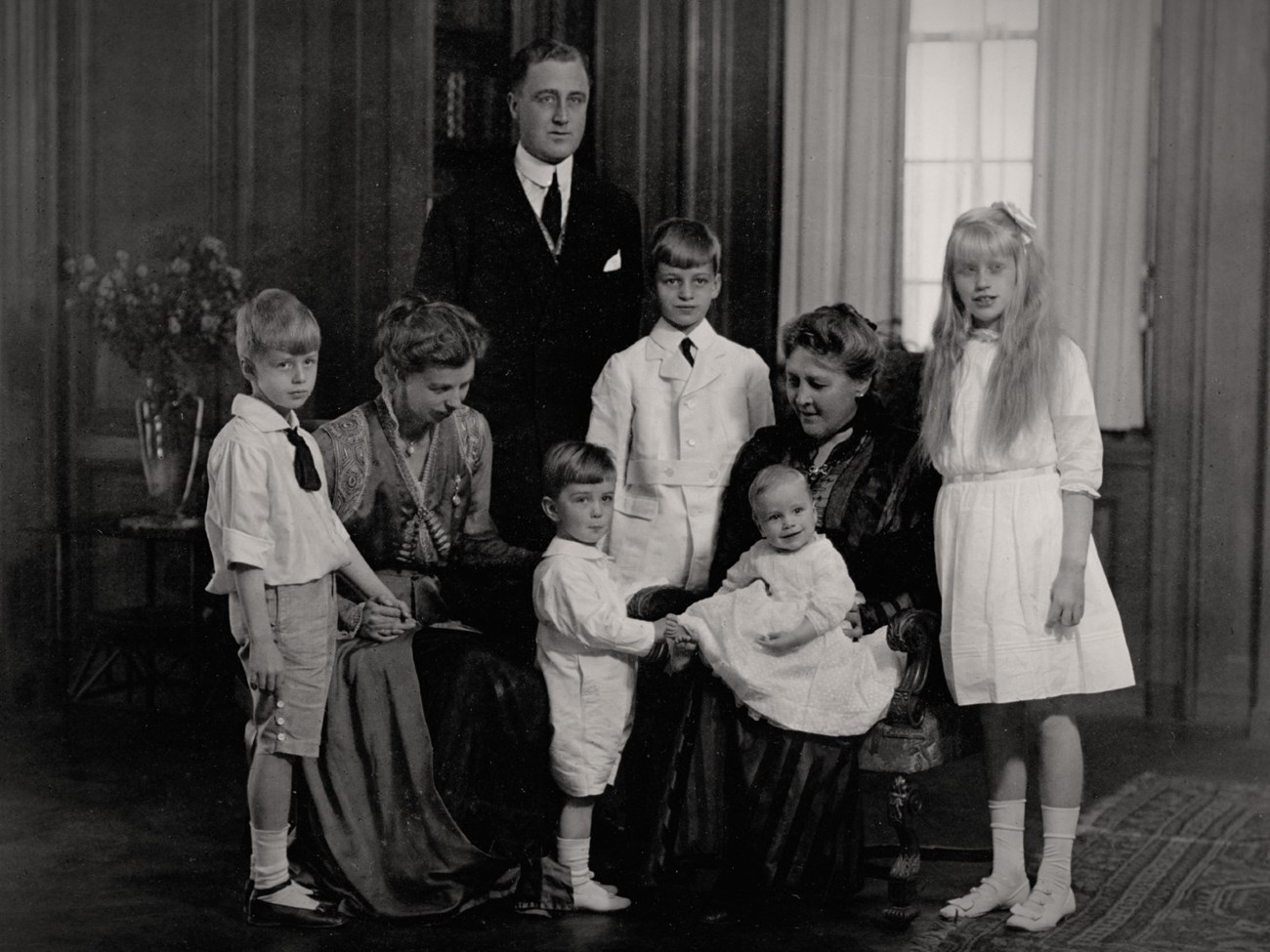 A family posed together near a window.