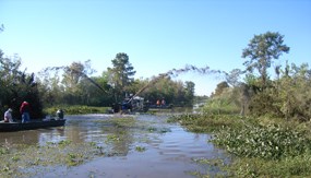 A dredge suctions mud from the bottom of a waterway and sprays it up on the banks