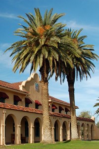 Kelso Depot with it's mission style archways, red tile roof, two tall palm trees, and green grass.