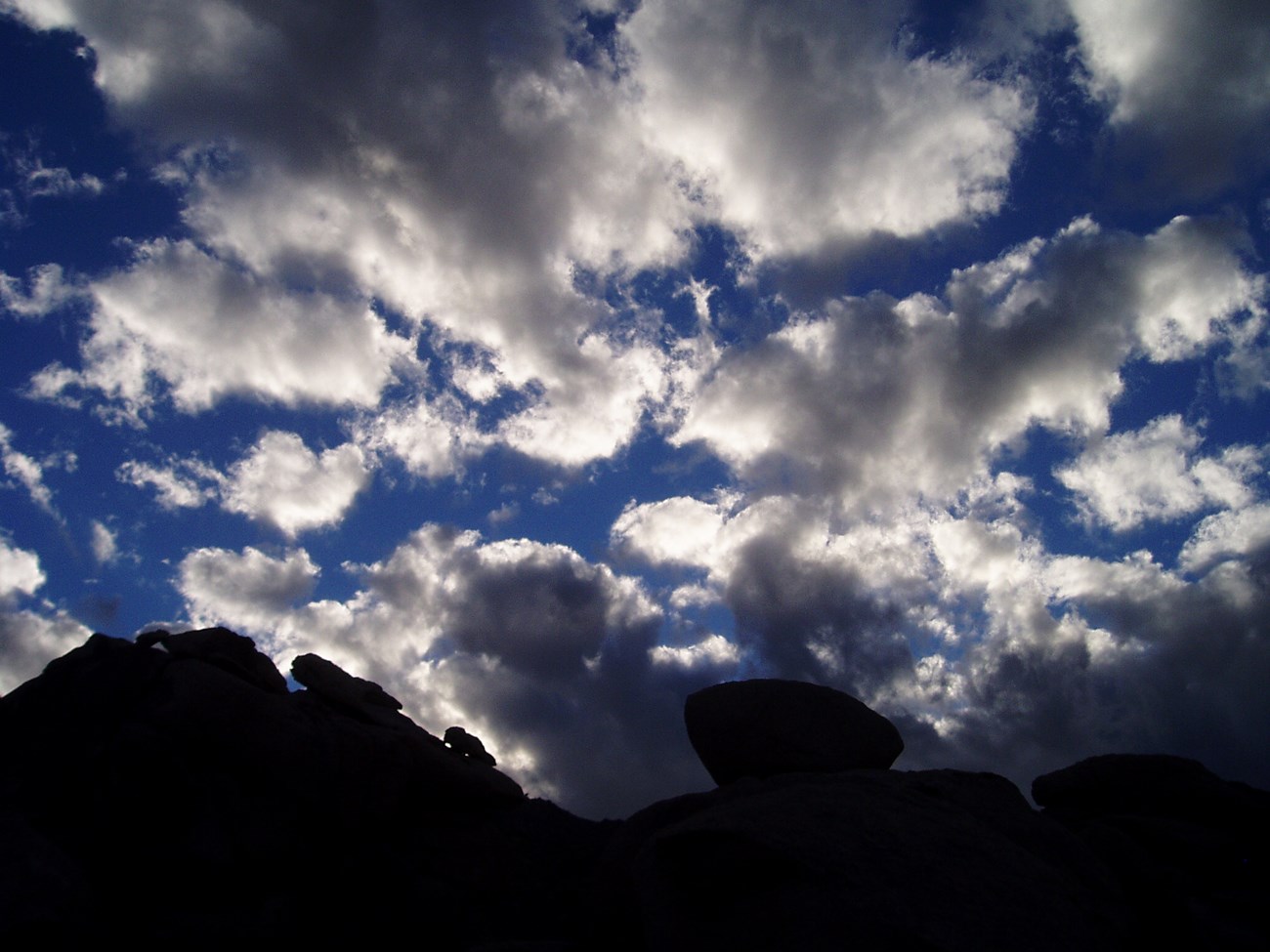 gathering clouds over the backlit Granite Mountains