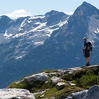 A hiker stands in front of a mountain view.