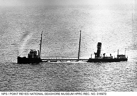 Water washes over the deck of a 1920s-era oil tanker that has run aground on a submerged reef.