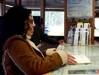 A woman reads a Braille book on top of a high countertop.