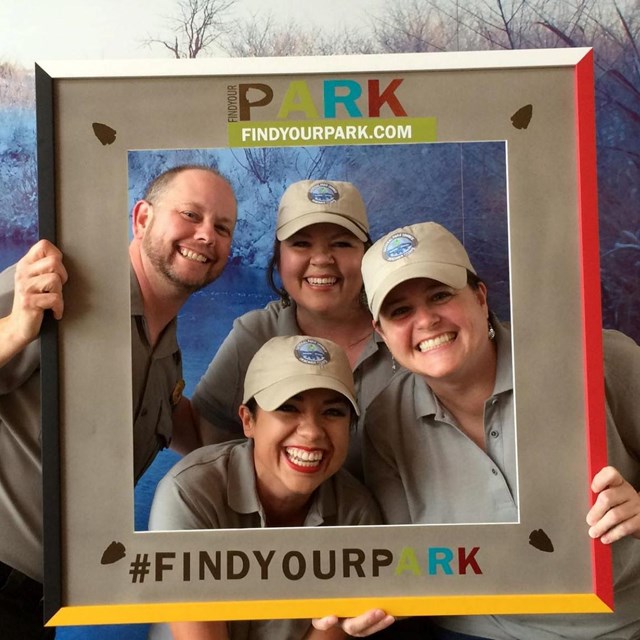 Three teacher ranger teachers pose with ranger in a frame