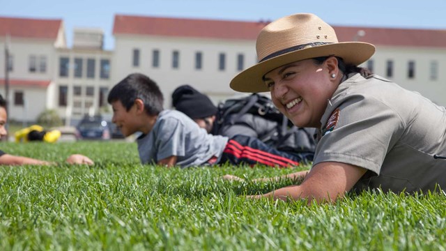 ranger on grass with kids and fort in background