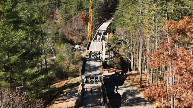 Construction crews and a large crane on a bridge under construction 