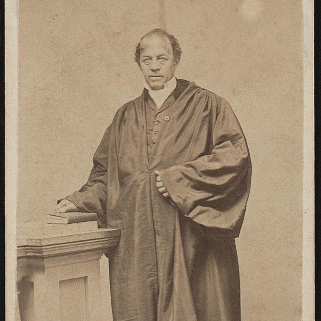 Reverend stands next to an altar wearing ceremonial robes.