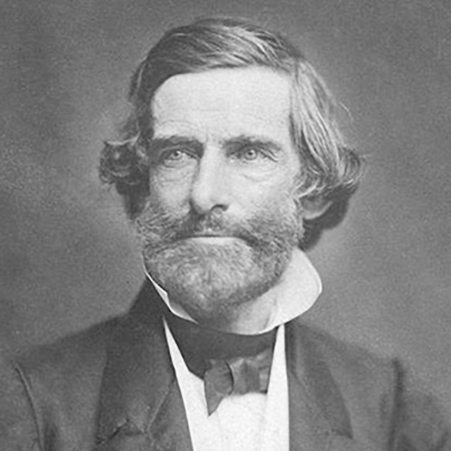 Three quarter profile portrait of a white man wearing a suit.