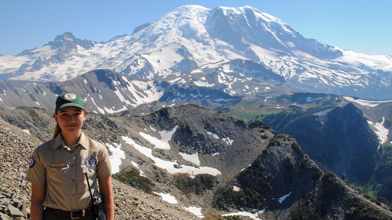 ranger standing with volcanic mountain in background