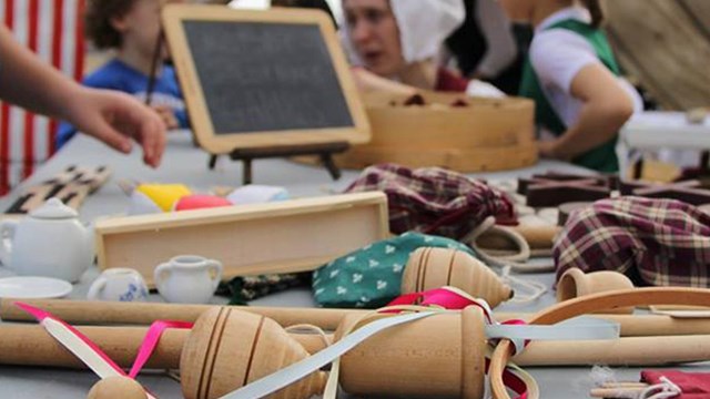 Historic toys on a table, with children and a teacher in the background