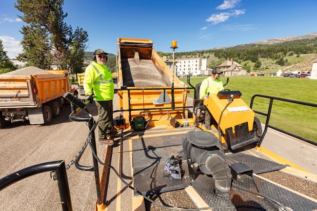 Two maintenance workers repaving a road