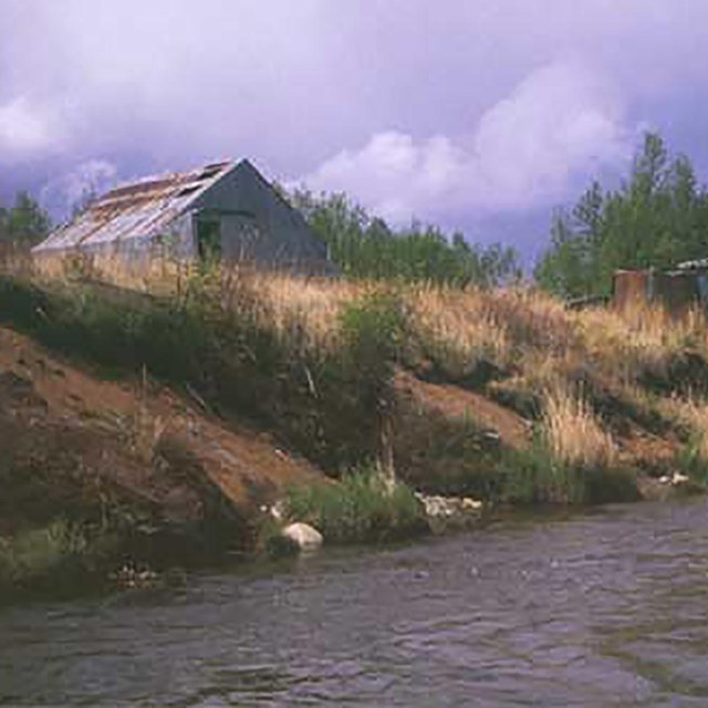 A photo of two structures made of metal alongside a river.