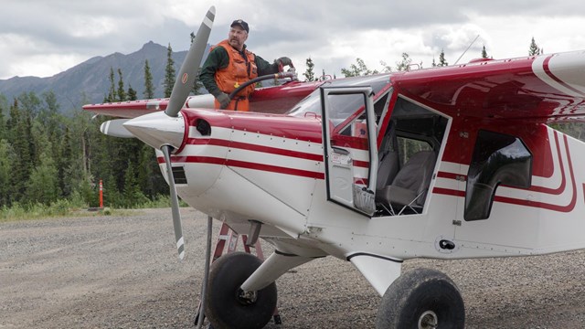 Pilot with his plane on a gravel runway