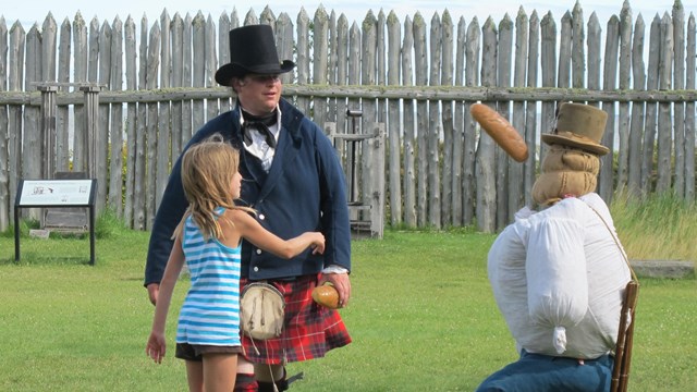 People in historic clothing tossing a loaf of bread.