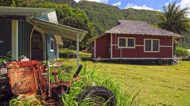 A red house with a grey roof, a lawn and a garage