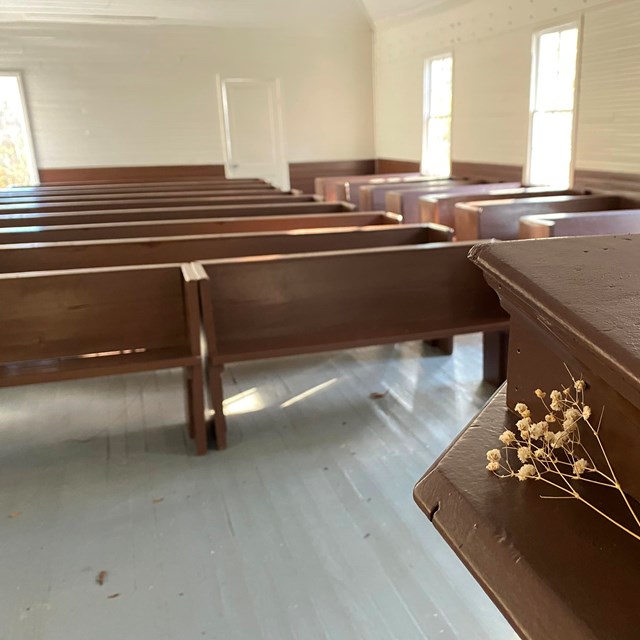 A small bunch of dried flowers sitting on a podium inside a church. 