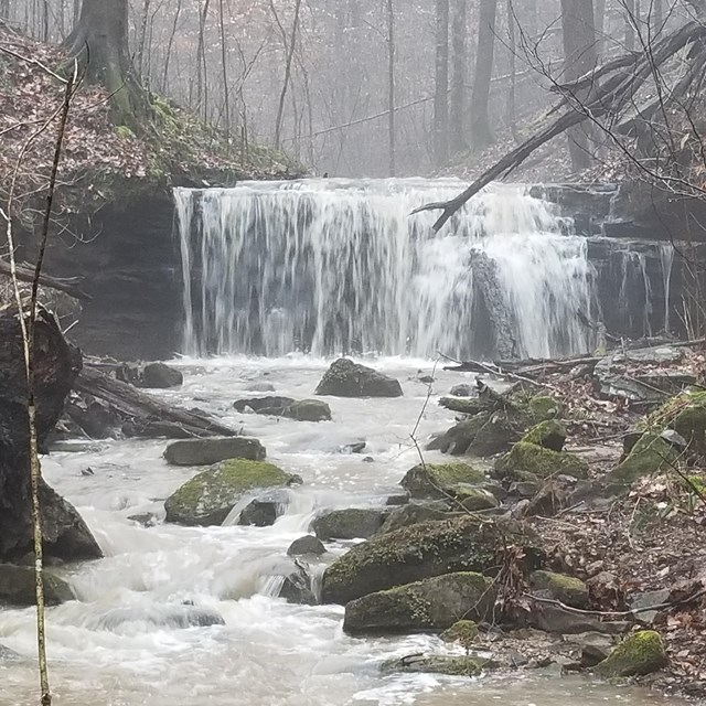 A fast moving waterfall flows into a stream.