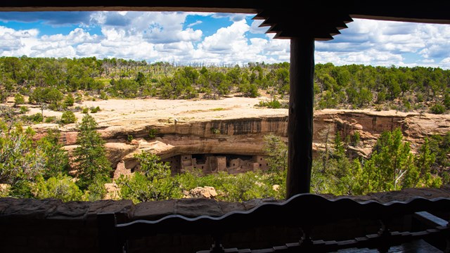 A view through a porch opening of an ancestral village set in a cliff alcove in a narrow canyon,