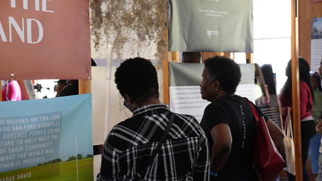 Two women read an exhibit about identity and land ownership.