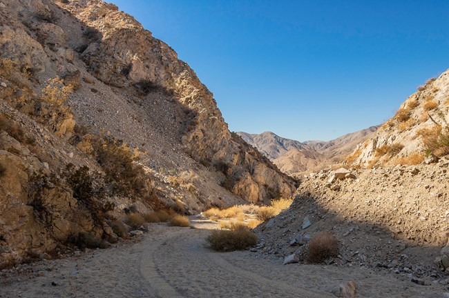 A sandy road with sloping canyon walls on either side.