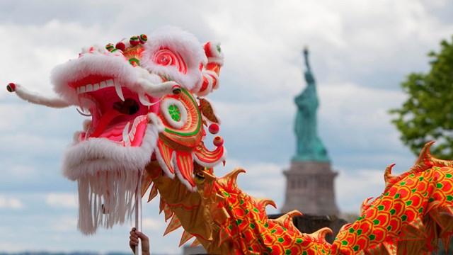 Large dragon puppet with the Statue of Liberty in the background
