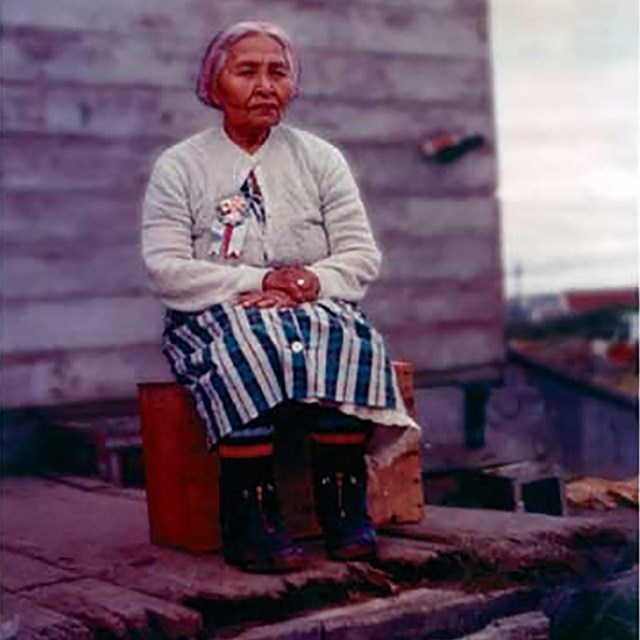 An image of a woman sitting with her hands crossed across her lap.