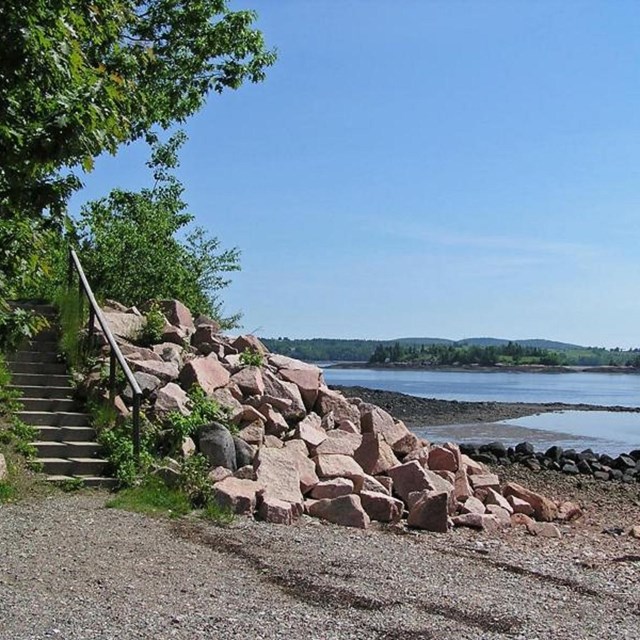 rocky beach with a view across the river toward Saint Croix Island.