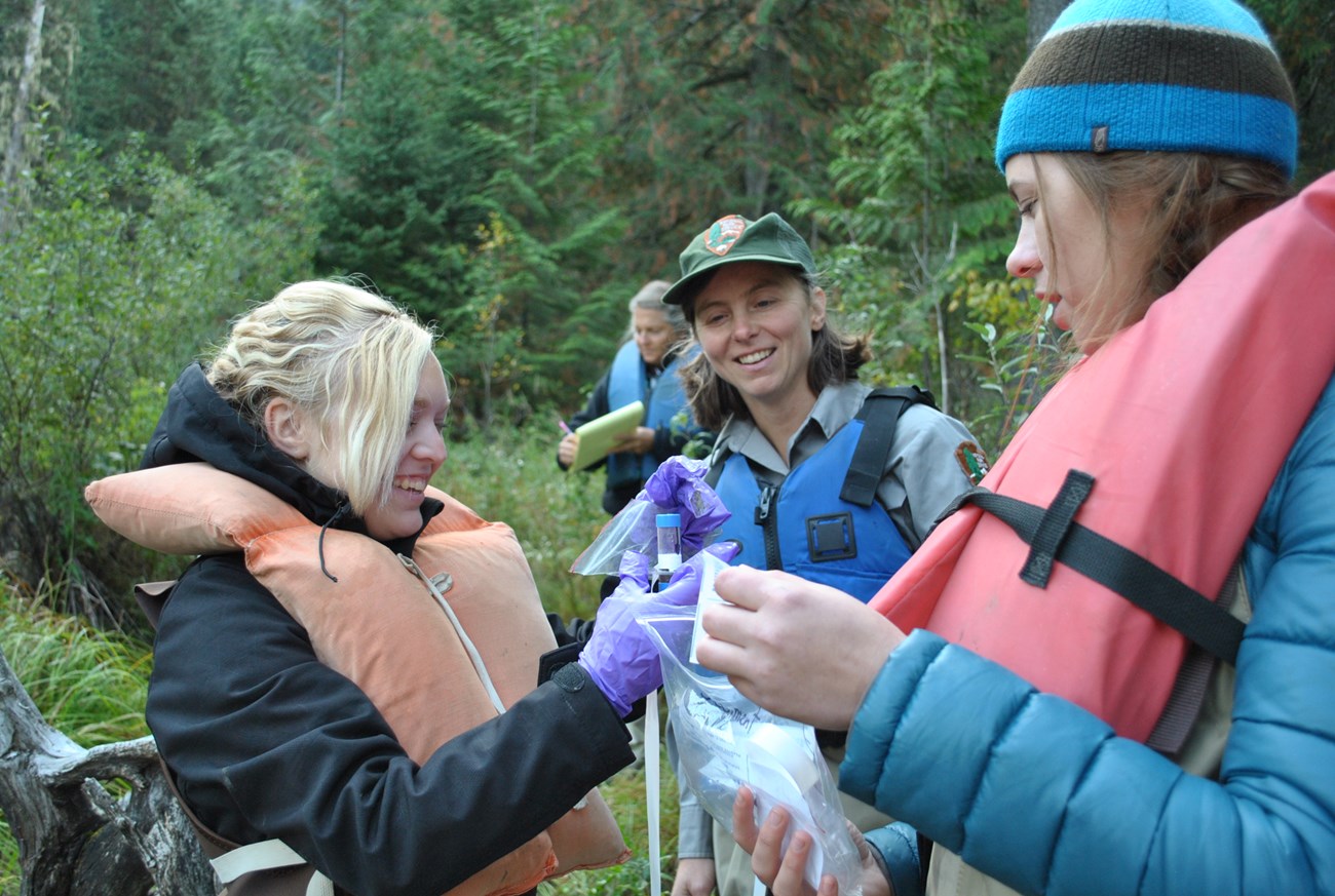 a ranger helps two students take a measurement