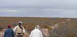 Three people walk across New Mexico desert landscape on El Camino Real de Tierra Adentro