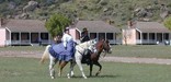 A lady riding side-saddle being escorted across the parade ground by cavalry trooper.