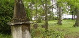 A large memorial sits with other gravestones in a forested cemetery at Brainerd Mission in Chattanooga, Tenneessee