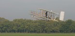 Replica of Wright Flyer III soaring above Huffman Prairie Flying Field.