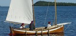 A wooden sailboat, called a Mackinaw, approaches a dock at Grand Portage.