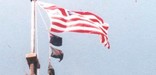 stripes of red, white, & blue streak across a blue sky on a cloudy day