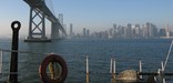Photo taken from the deck of BALCLUTHA under tow passing under the SF Oakland Bay Bridge with the SF skyline in the background.