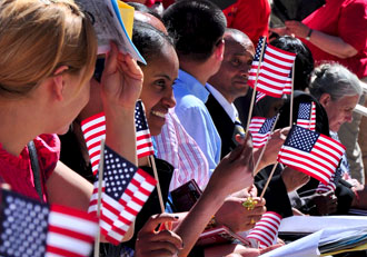 New citizens hold flags at a naturalization ceremony at Mount Rushmore National Memorial. New citizens hold flags at a naturalization ceremony at Mount Rushmore National Memorial.