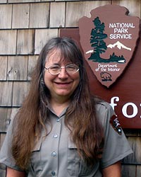 Female park ranger poses in front of arrowhead sign