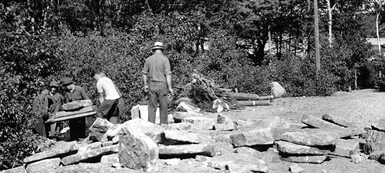 Five men haul granite blocks.