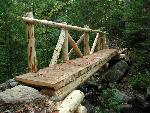 Wooden bridge stretches across a wooded ravine.